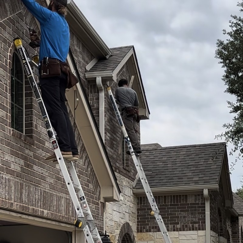 Two Dazzl installers on ladders mounting permanent LED channel under the soffit of a Texas home