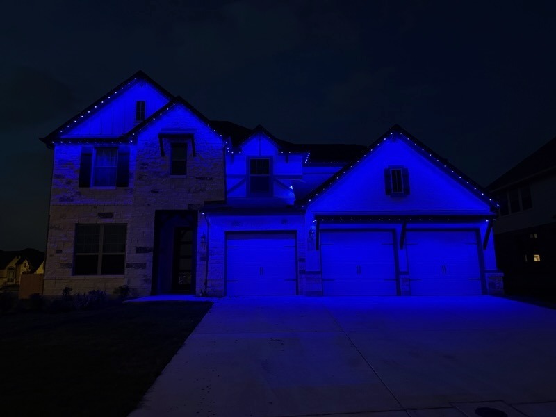 Texas Hill Country home washed in deep blue and purple Halloween LED lighting