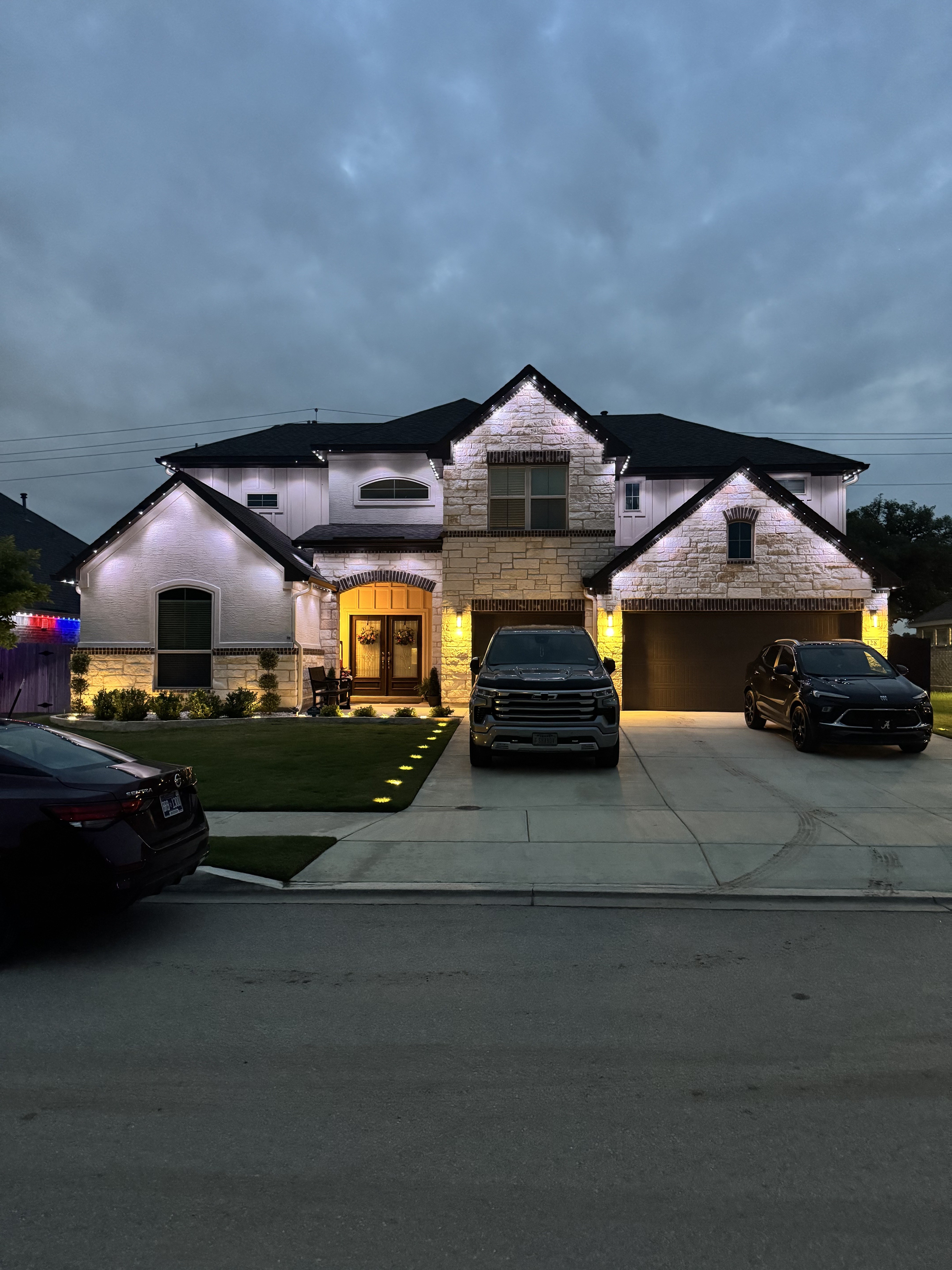White-stucco Texas home with soft warm white roofline lighting at dusk