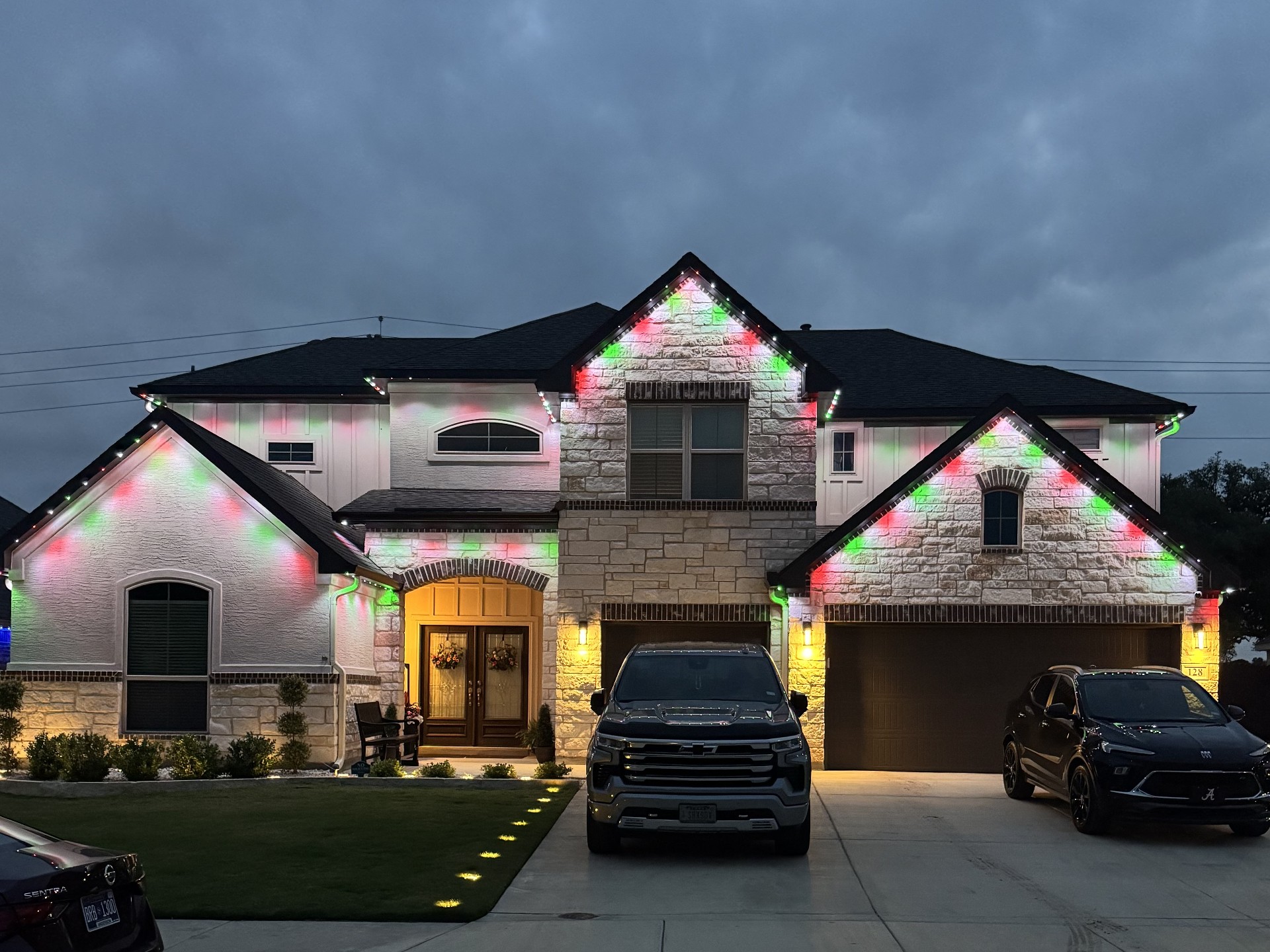 Same white-stucco Texas home with red and green Christmas permanent LED lighting